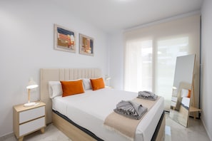 A modern hotel room with a large bed, two bedside tables, a nightstand, a mirror, and artwork on the wall. - Calma - Your Mediterranean retreat (Orihuela Costa)