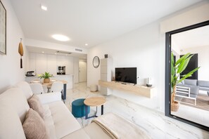 Ein modernes Wohnzimmer mit einer Couch, einem Couchtisch und einem an der Wand befestigten Fernseher.
