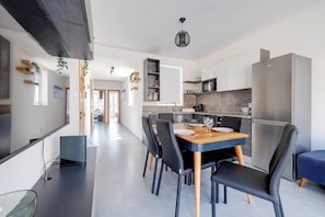 A modern kitchen with a dining area, featuring a central island, built-in appliances, and a hanging light fixture. - Stunning 2BR Holiday Penthouse in Central Sliema (Sliema)