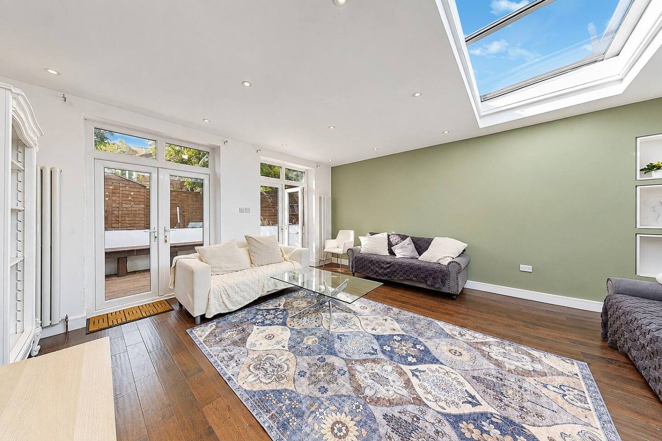 A spacious living area with a glass coffee table, two sofas, and a patterned rug.