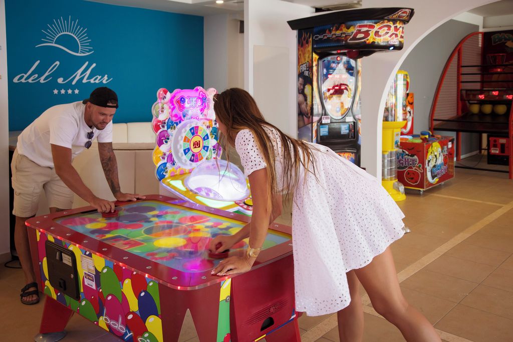 Un hombre y una mujer jugando un juego de arcade colorido con una ruleta de premios.