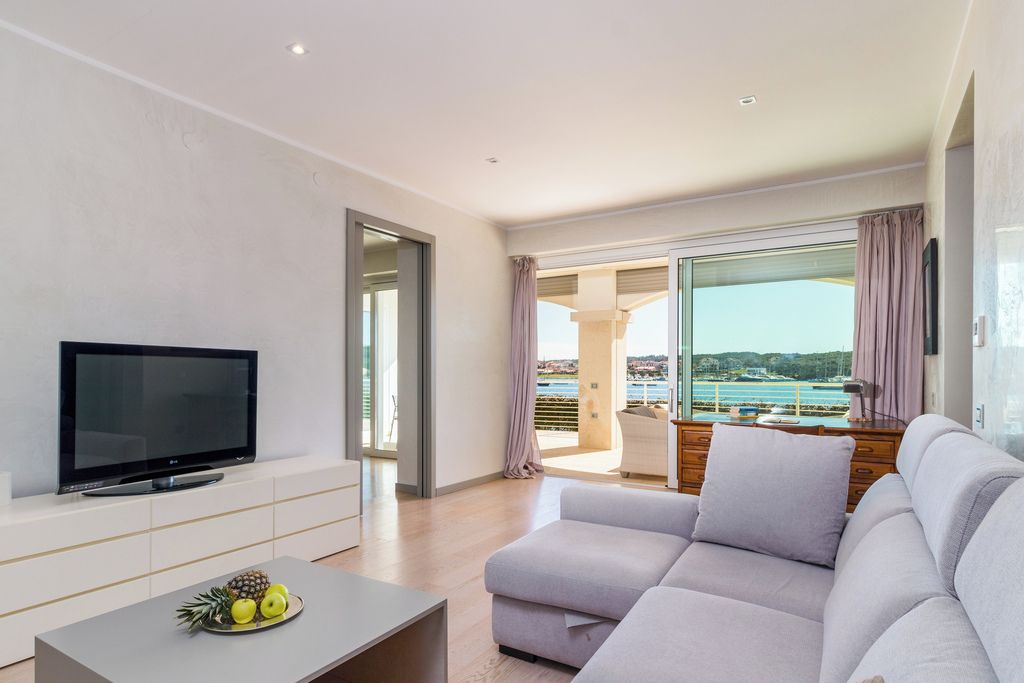 A modern living room with a flat-screen TV, a sofa, and a coffee table with fruit.