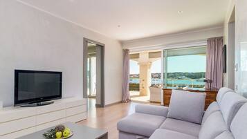 A modern living room with a flat-screen TV, a sofa, and a coffee table with fruit.