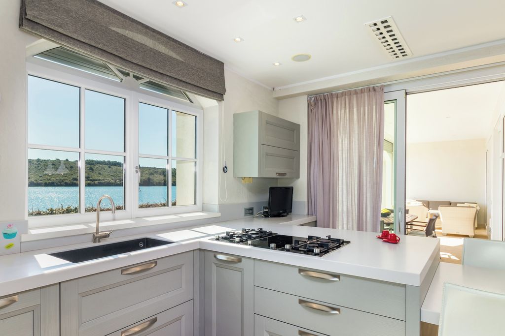 Una cocina moderna con estufa integrada, un lavamanos y ventana con vistas al agua.