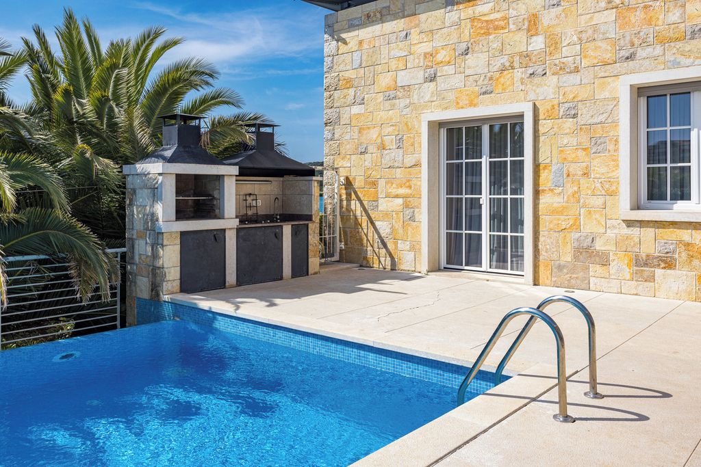 A swimming pool with a stone wall and a grill area.