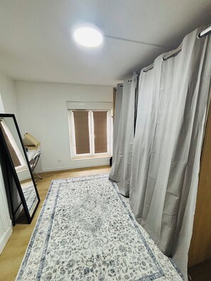 Ein Zimmer mit Fenster, Tür, einem gemusterten Teppich und einem Vorhang.