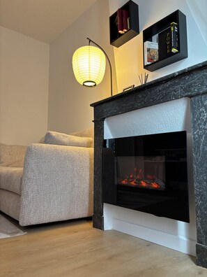 Ein modernes Wohnzimmer mit Kamin, einer Couch und einem an der Wand befestigten Bücherregal.