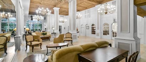 A spacious lobby with high ceilings, chandeliers, and classic furniture.
