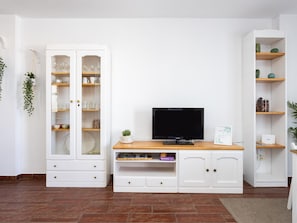Ein Wohnzimmer mit Fernseher, weißen Schränken und Regalen.