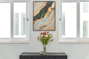 A room with a marble artwork, a vase with flowers, and a dark wooden cabinet. - Spacious 4 Bedroom Apartment in Peaceful Gharghur (Hal Gharghur)