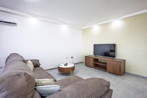 A modern living room with a sofa set, a coffee table, and a flat-screen TV on a wooden stand. - Spacious 4 Bedroom Apartment in Peaceful Gharghur (Hal Gharghur)