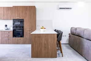 Una cocina moderna con armarios de madera, horno empotrado y encimera blanca.