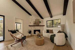 A living room with a stone fireplace, a white sofa, a wooden coffee table, and a hanging chair. - Longridge Crest - Gated Studio City Canyon Home (Studio City)