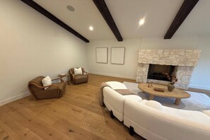 Una sala de estar con chimenea de piedra, dos sofás, una mesa de centro y una mesita auxiliar.