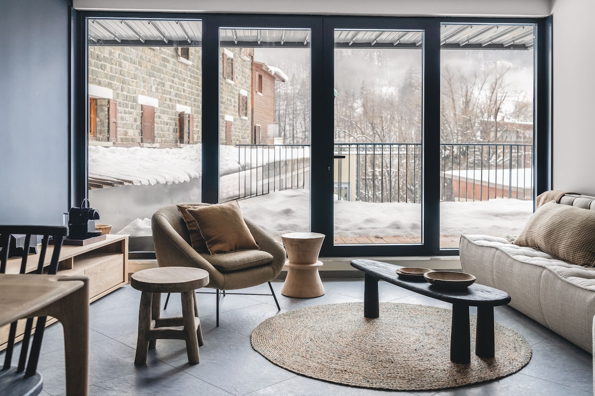 A modern living room with a large sliding glass door leading to a snowy outdoor area.