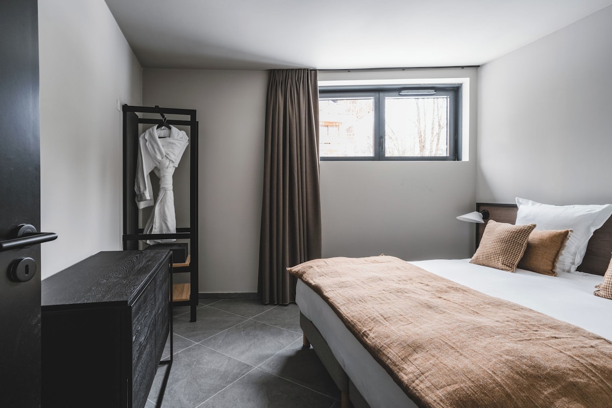 A hotel room with a bed, bedside table, and a wardrobe.