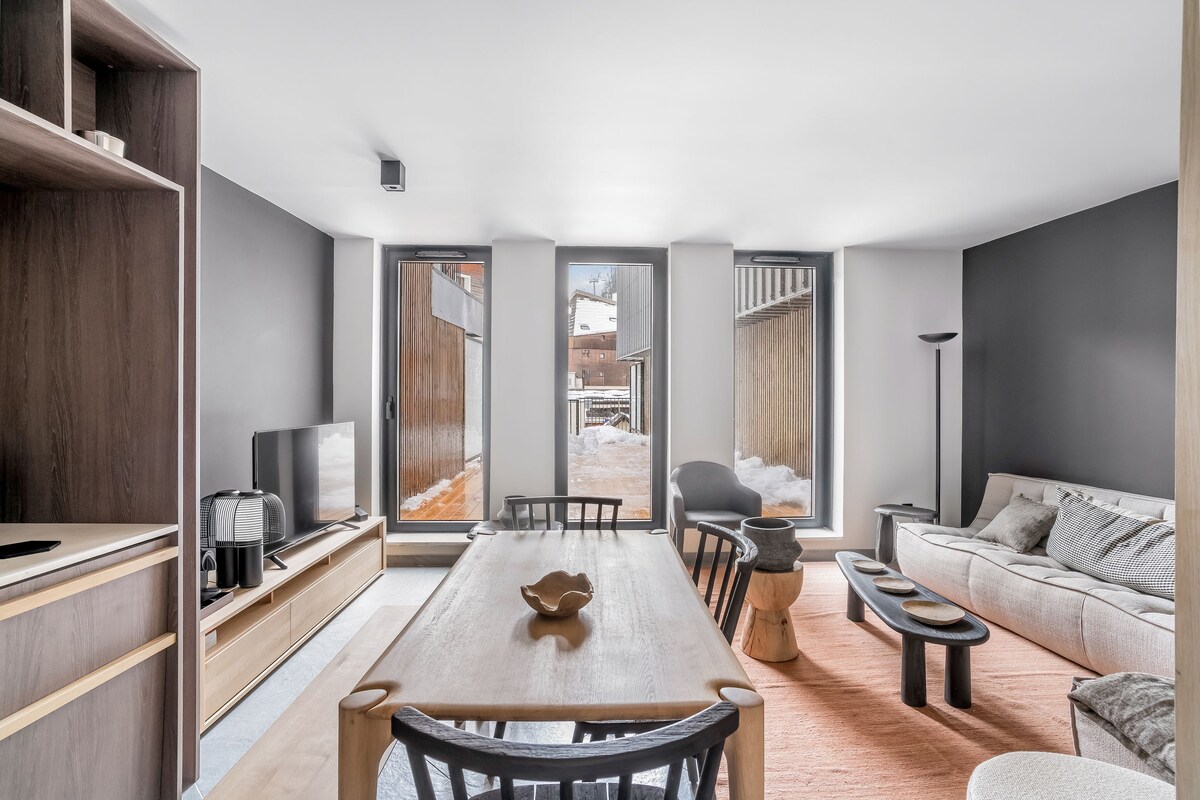 A modern living room with a wooden dining table, a sofa, and a TV.