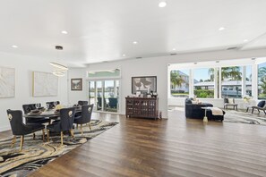 A spacious living area with a dining set, a large window, and a view of the outdoors. - Waterfront. Pool, Hot Tub, FirePit, Near Beach (Jacksonville)