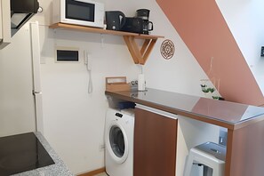 A compact kitchen with a microwave, coffee maker, and a washing machine. - Loft con parrilla cochera y gran diseño (Buenos Aires)