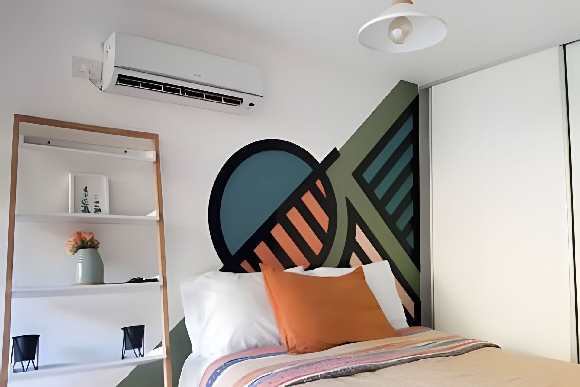 Un dormitorio moderno con cama, aire acondicionado de pared, estantería y un adorno en la pared.