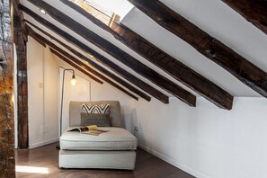 A cozy reading nook with a cushioned bench, a patterned pillow, and a wall-mounted light fixture. - Penthouse near Plaza Mayor, Madrid (Madrid)