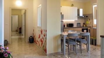 Una cocina moderna con comedor, un pasillo que conduce a otra habitación y una pared decorativa.