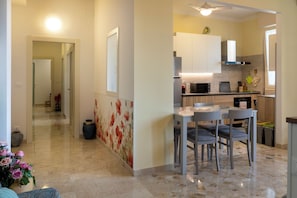 A modern kitchen with a dining area, a hallway leading to another room, and a decorative wall. - HouSmart Giambologna 8 (Bologna)