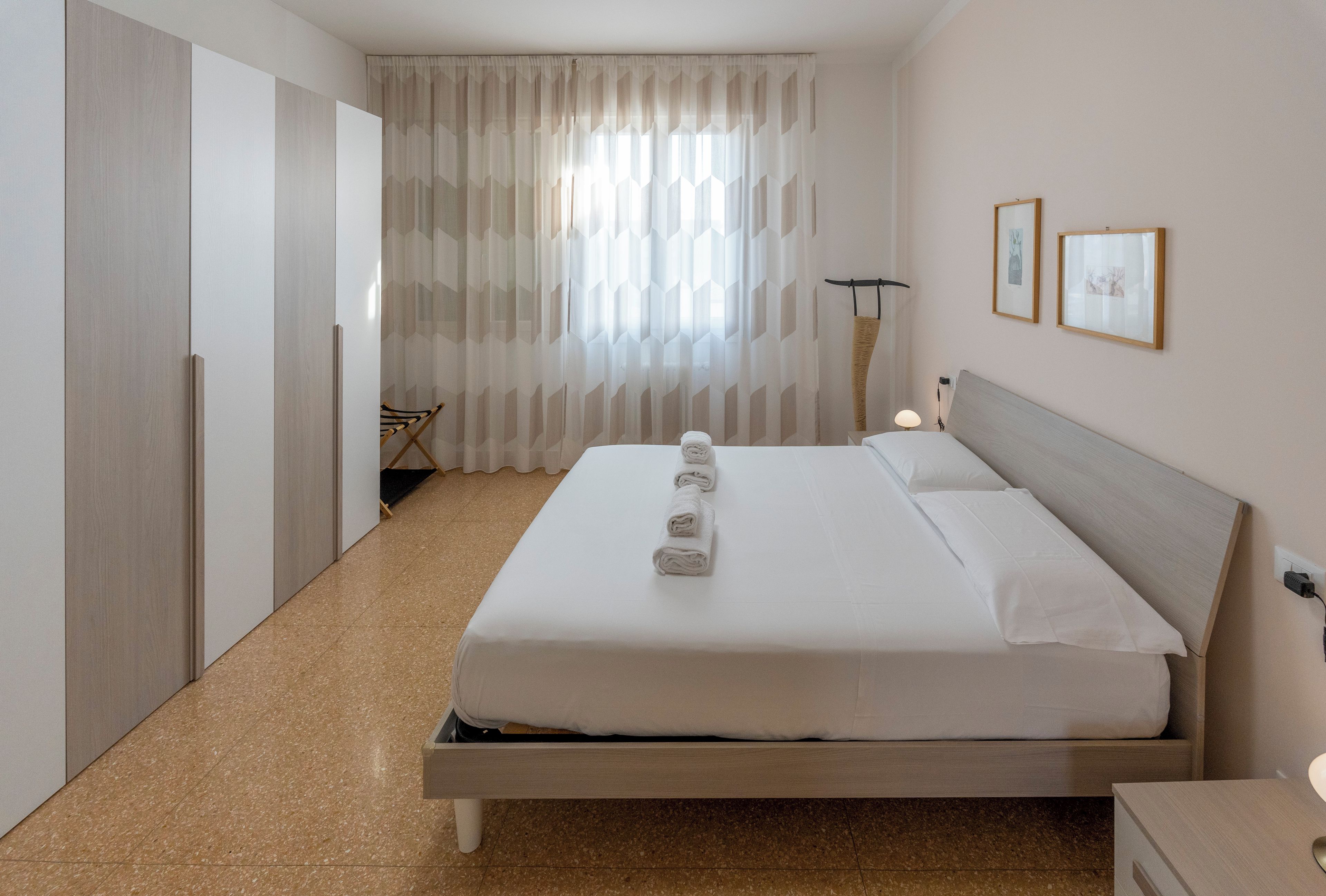 Une chambre d’hôtel avec un lit, une armoire, une chaise et une lampe.
