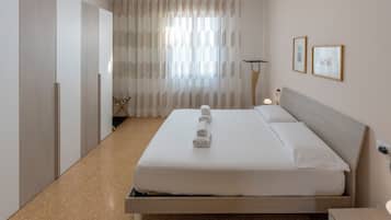 Une chambre d’hôtel avec un lit, une armoire, une chaise et une lampe.