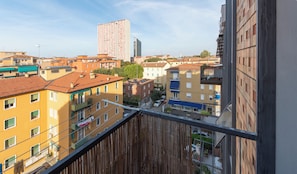 Een hoog gebouw met meerdere balkons en een uitzicht op een stadsbeeld.