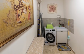 Een kleine wasruimte met een wasmachine, een droogrek en een klein wastafeltje.