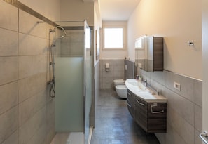A modern bathroom with a glass shower enclosure, a toilet, and a vanity with a mirror. - HouSmart Giambologna 8 (Bologna)