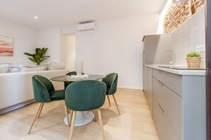 A modern kitchen with grey cabinets, a round dining table with two chairs, and a white countertop. - Apartment with Balcony, La Latina (Madrid)