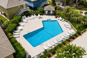 A rectangular pool with a surrounding deck, lounge chairs, and a small building with a staircase. - Beach House | Walk to Beach | Golf Carts OK (Myrtle Beach)