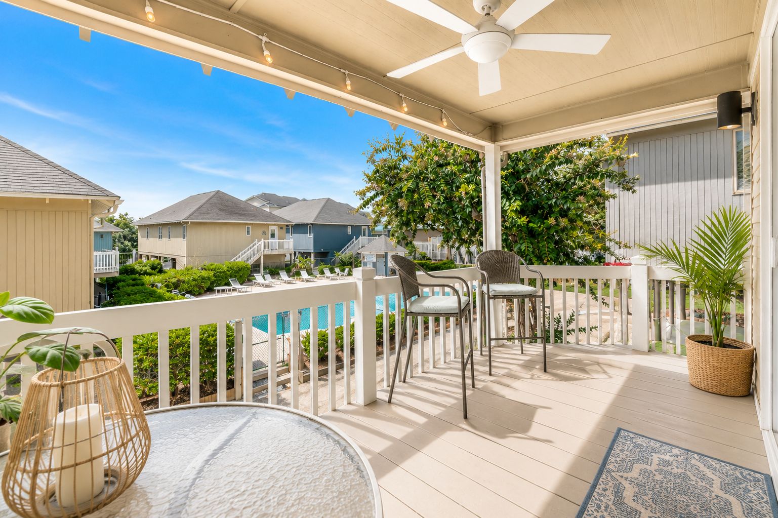 A covered outdoor area with a pool, lounge chairs, and a ceiling fan.
