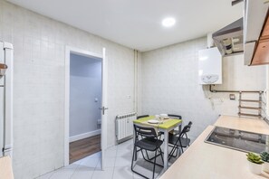 A compact kitchen with a dining table, chairs, a built-in stove, and a radiator. - Family Apartment, Heart of Madrid (Madrid)