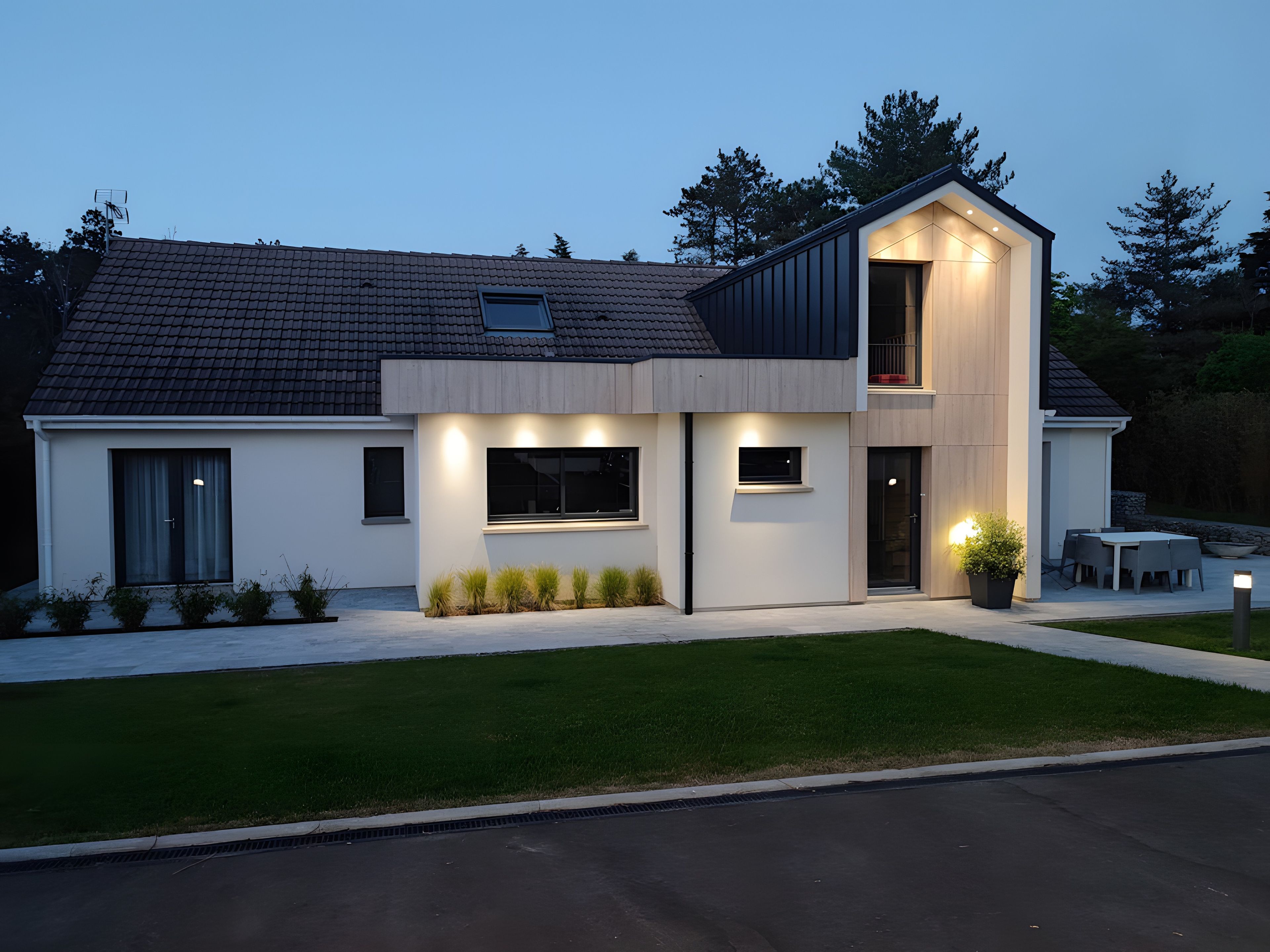 Une maison moderne à deux étages, dotée d’un toit plat, de grandes fenêtres et d’une pelouse bien entretenue.