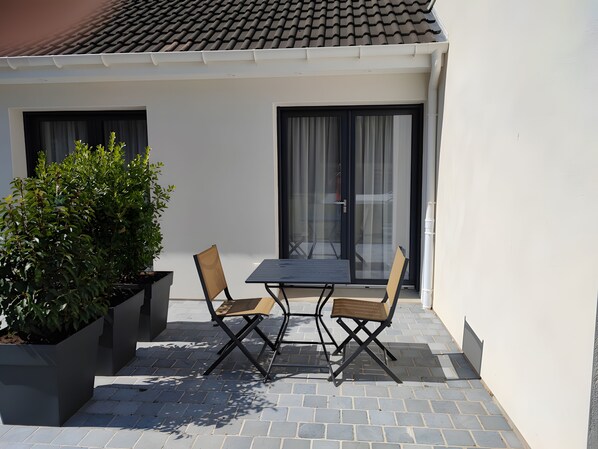 Een terras met een tafel en stoelen, een potplant en een schuifdeur van glas.