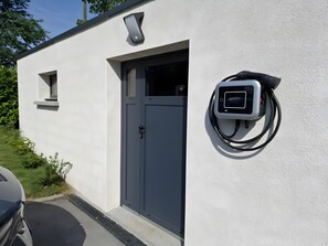 Een gebouw met een grijze deur en een laadstation aan de muur.