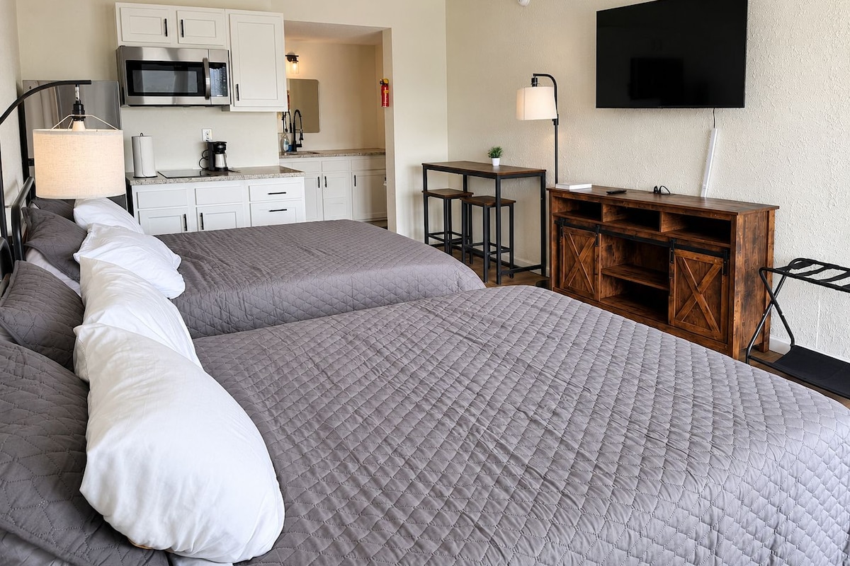 Et hotelværelse med en stor seng, tekøkken, TV og et skrivebord.