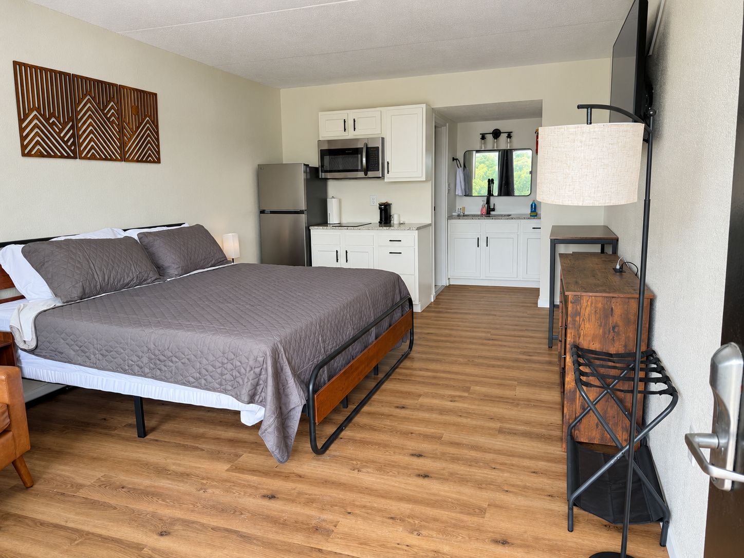 Una habitación pequeña con cama, kitchenette y un rincón de comedor.