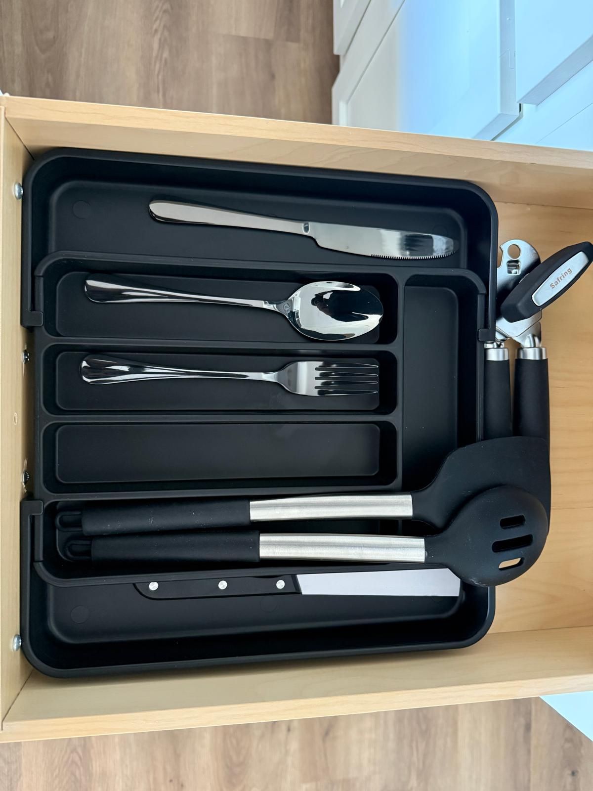 Un cajón con un estuche negro que contiene varios utensilios de cocina.