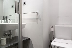 Een badkamer met toilet, wastafel en douchehoek.