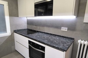A compact kitchen with white cabinets, a granite countertop, and a built-in oven. - Bright room in Apartment, Chamartin (Madrid)