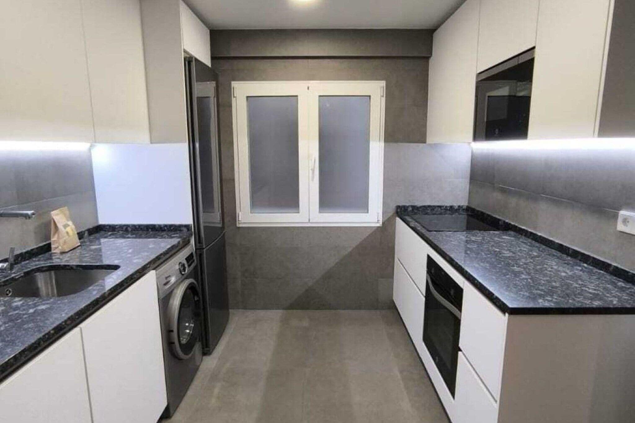 Une cuisine compacte équipée d’un lave-linge intégré, d’un four à micro-ondes et d’une cuisinière.