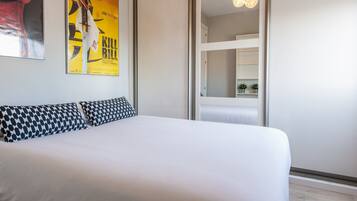 Une chambre d’hôtel avec un grand lit, une affiche au mur et un miroir qui reflète la pièce.