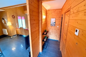 A wooden interior with a hallway leading to a room with a bed, a lamp, and a window with curtains. - Family Chalet with Fireplace, Mont-Dore (Mont-Dore)