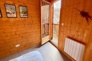 A wooden cabin room with a bed, a window, and two framed pictures on the wall. - Family Chalet with Fireplace, Mont-Dore (Mont-Dore)