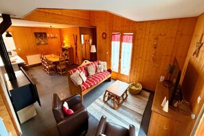 A wooden cabin interior with a dining area, a sofa, and a small table. - Family Chalet with Fireplace, Mont-Dore (Mont-Dore)
