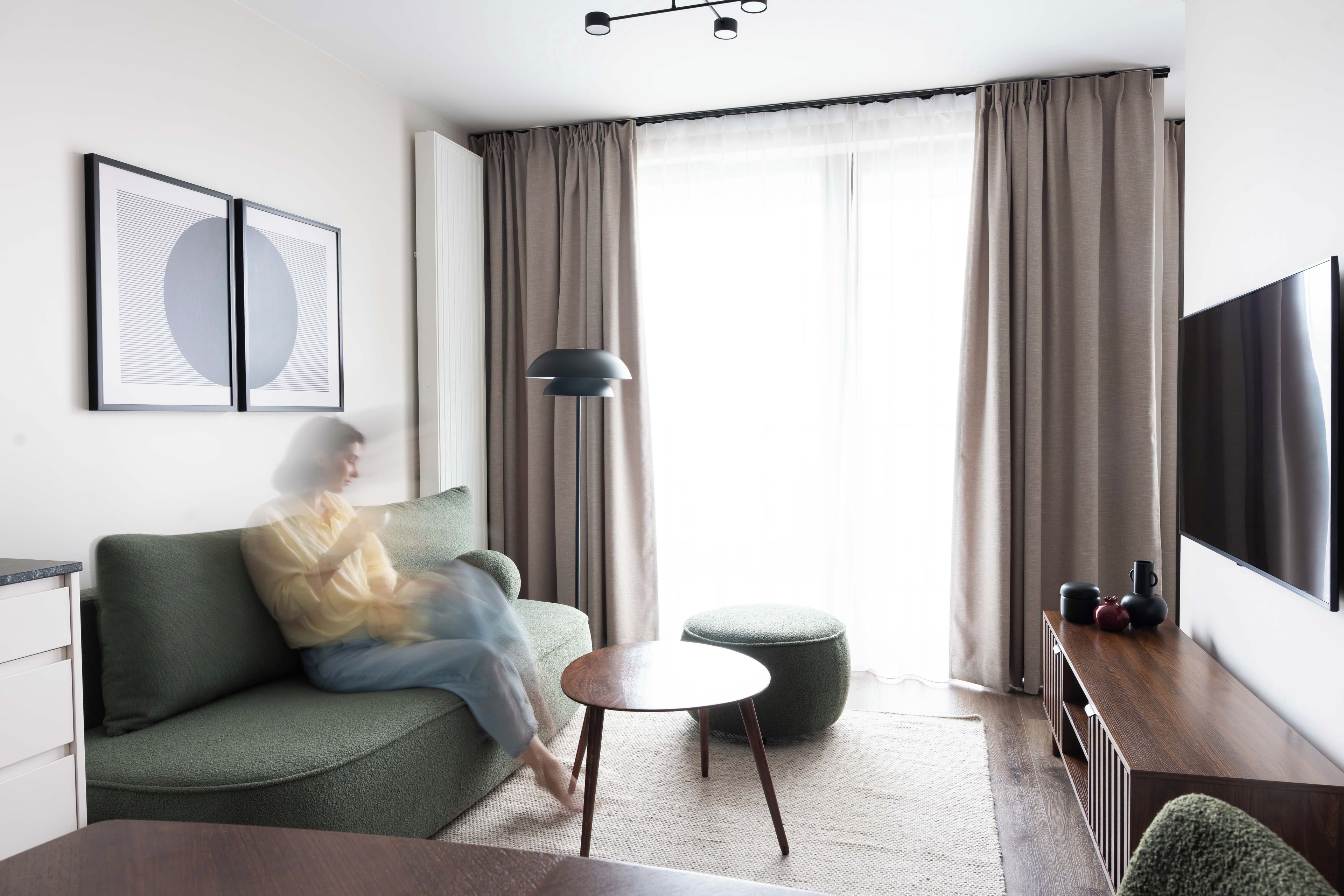 A modern living room with a sofa, a side table, a floor lamp, and a flat-screen TV.